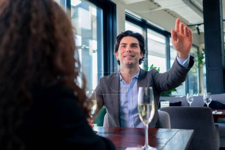 Foto de Un hombre de negocios llama a un camarero para hacer un pedido en un establecimiento de élite el concepto de hospitalidad y servicio - Imagen libre de derechos