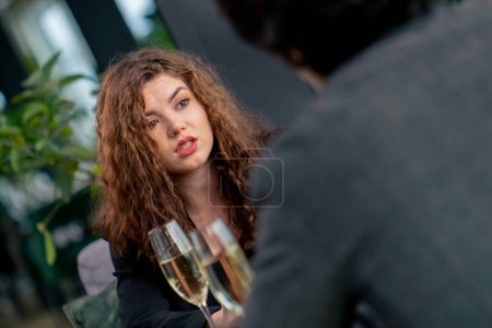 Photo for Portrait of young upset curly woman quarreling on business meeting with colleague or on date with man with glasses champagne - Royalty Free Image