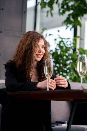 Foto de Retrato de una joven rizada en una reunión de negocios con un colega o en una cita con un hombre con copas celebración de champán - Imagen libre de derechos