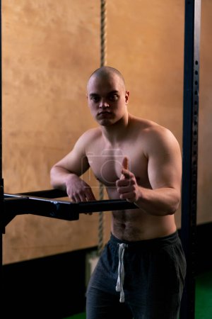 Photo for In the gym a bald trainer stands near the horizontal bar for push-ups and pull-ups points his finger - Royalty Free Image