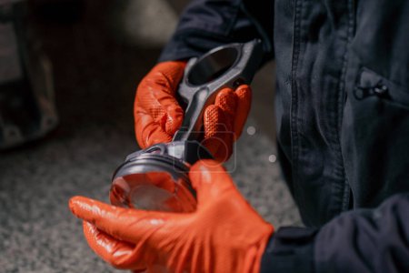 Photo for Close-up At a service station on the table a young engine repairman assembles a new piston part - Royalty Free Image