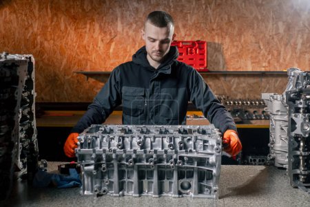 Photo for At a service station on the table a young engine repairman manually cranks the crankshaft in the engine - Royalty Free Image