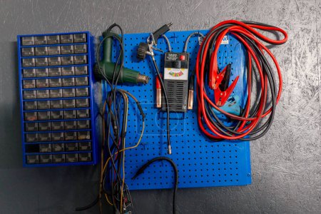 Foto de Primer plano en una estación de servicio en una pared gris hay un panel azul con herramientas para trabajar con la batería - Imagen libre de derechos