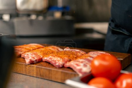 Foto de Primer plano en la cocina profesional en un chef en una chaqueta negra sales y pimientos costillas - Imagen libre de derechos
