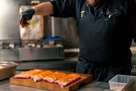 Téléchargez les photos : Gros plan dans une cuisine professionnelle dans un chef dans une veste noire poivrons côtes qui reposent sur une planche de bois - en image libre de droit