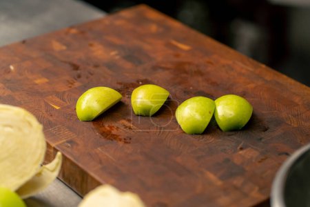 Photo for In a professional kitchen green chopped pieces of green apple lie on a wooden board - Royalty Free Image