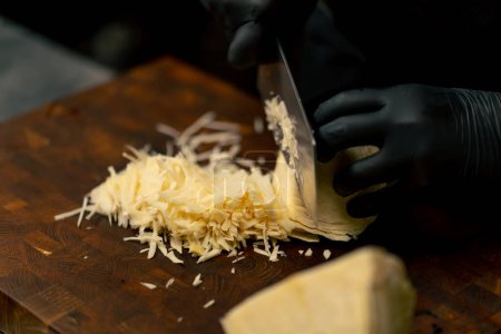 Foto de Primer plano en una cocina profesional con guantes negros corta la col en el tablero de madera - Imagen libre de derechos