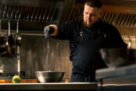 Téléchargez les photos : Dans une cuisine professionnelle portant des gants noirs salant le chou dans un bol en fer - en image libre de droit