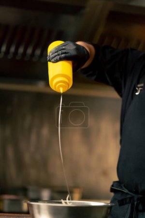fermer dans la cuisine professionnelle gants noirs versent de l'huile sur le chou dans un bol de fer