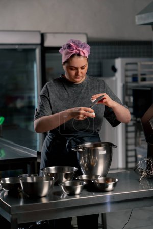 Téléchargez les photos : Dans une cuisine professionnelle au-dessus d'un boulanger de table en fer casse un oeuf dans un grand bol en fer - en image libre de droit