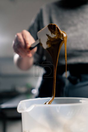 Foto de Primer plano en un panadero de cocina profesional saca mantequilla de maní con una espátula - Imagen libre de derechos
