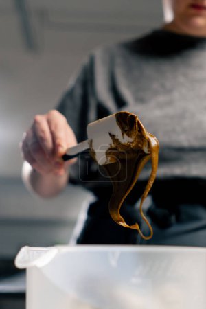 Téléchargez les photos : Gros plan dans une boulangerie de cuisine professionnelle sort le beurre d'arachide avec une spatule - en image libre de droit