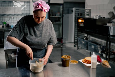 Foto de En una cocina profesional panadero saca mantequilla de maní con una espátula - Imagen libre de derechos
