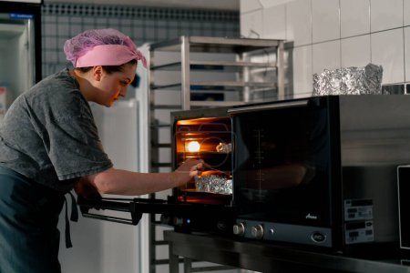 Téléchargez les photos : Dans une cuisine professionnelle, un boulanger sort du four des biscuits prêts à l'emploi - en image libre de droit