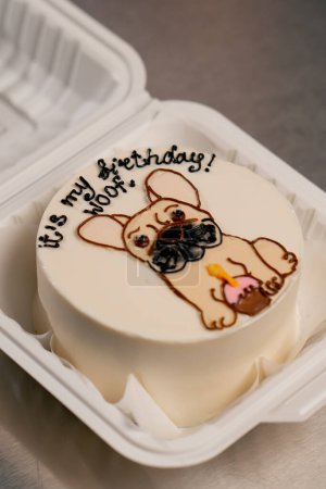 Foto de Primer plano de una panadera en una cocina profesional dibujando un perro en un pastel con crema - Imagen libre de derechos