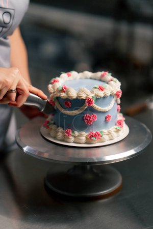 close-up in a professional kitchen a baker cuts a piece of blue cake with a knife