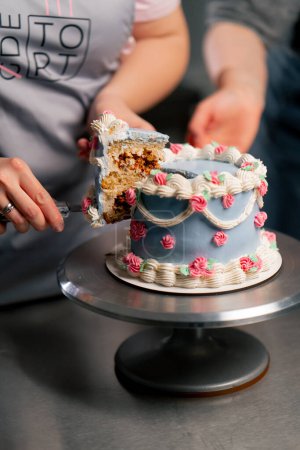 primer plano en una cocina profesional un panadero corta un pedazo de pastel azul con un cuchillo