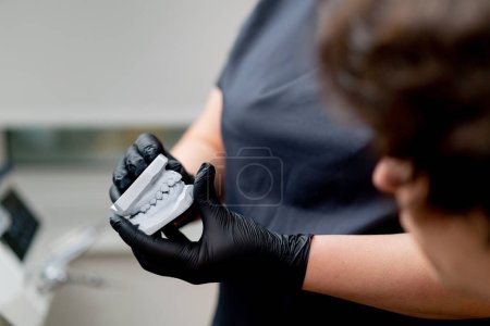 Foto de Primer plano odontológico odontólogo rubio en un uniforme negro consultar a un paciente que muestra un yeso dental - Imagen libre de derechos