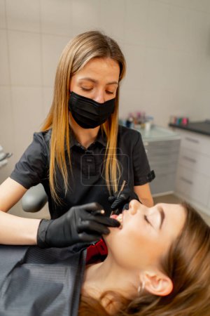 Photo for In the dental office of a girl a dentist examines the oral cavity of a girl patient - Royalty Free Image