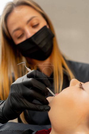 Téléchargez les photos : Gros plan dans le cabinet dentaire d'une fille un dentiste examine la cavité buccale d'une patiente - en image libre de droit