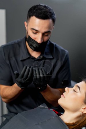 Foto de En un consultorio dental un dentista masculino lleva a cabo una consulta mostrando sus manos a una joven hermosa - Imagen libre de derechos
