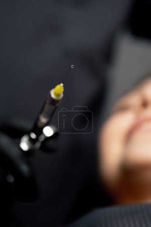 Foto de Primer plano en un consultorio dental un dentista masculino le da una inyección anestésica a una joven hermosa - Imagen libre de derechos