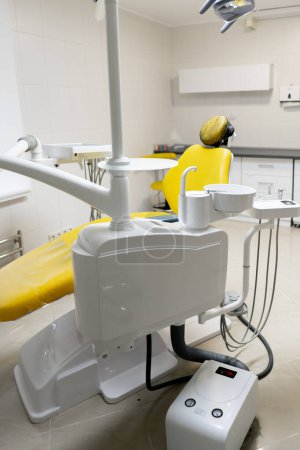 Foto de Consultorio dental blanco estéril listo para robots silla amarilla para el paciente y el equipo blanco - Imagen libre de derechos