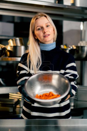 Foto de Una joven en la cocina se destaca y sostiene un tazón de batata demostrando el producto a la cámara - Imagen libre de derechos