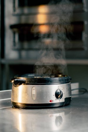 Téléchargez les photos : Dans la cuisine de l'établissement sur la table de cuisson, il y a un vapeur en fonctionnement vapeur sort de celui-ci - en image libre de droit