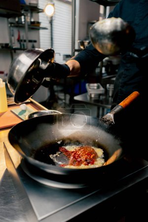Photo for Close-up of pouring red meat ingredients into hot frying pan frying an egg - Royalty Free Image