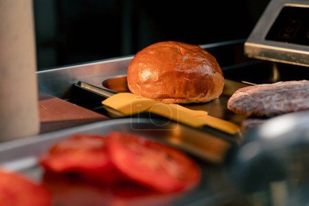 Foto de Primer plano en la mesa de la cocina del establecimiento hay una mitad de un bollo de hamburguesa al lado del queso - Imagen libre de derechos