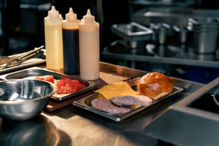 In the restaurants kitchen there are gravy boats and all the ingredients for assembling a burger