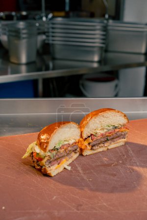 Photo for Close-up in the kitchen of a cut ready-made beef burger two halves lying on a board - Royalty Free Image