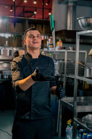 Téléchargez les photos : Un chef de cuisine vêtu d'une veste noire démontre la capacité de lancer un couteau en l'air - en image libre de droit