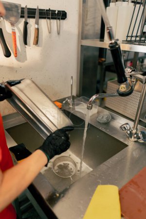 Téléchargez les photos : Gros plan d'une femme qui lave de la vaisselle sale dans la cuisine après avoir utilisé un équipement professionnel - en image libre de droit