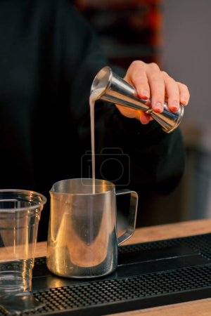 Téléchargez les photos : Fermer une jeune fille au bar verse la quantité requise d'alcool avec une tasse à mesurer dans un cocktail - en image libre de droit