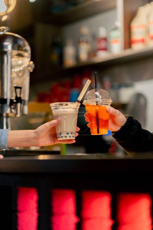 Foto de Primer plano de una máquina naranja para envasar bebidas con plástico en un mostrador de bar una chica que usa la máquina - Imagen libre de derechos