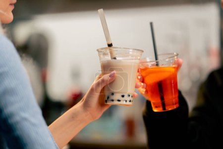 close-up of an orange machine for packaging drinks with plastic on a bar counter a girl using the machine