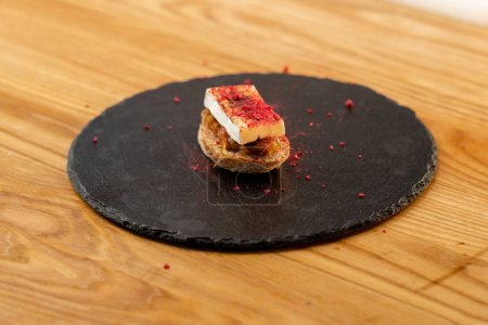 Foto de Primer plano de un sándwich de queso brie terminado con una base de cebolla sobre una tabla negra acostada sobre la mesa - Imagen libre de derechos