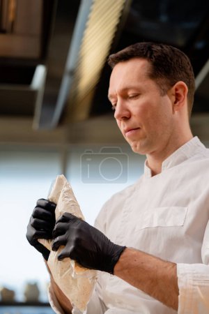 close-up of a chefs hands in black gloves spreading sauce from a bag onto a piece of baguette