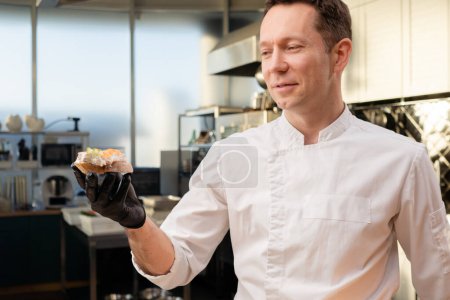 Foto de Primer plano de un chef con guantes negros demostrando un sándwich de salmón preparado - Imagen libre de derechos