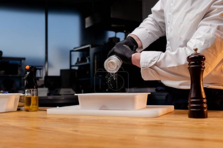 Téléchargez les photos : Un chef en uniforme blanc dans une cuisine professionnelle sels betteraves qui se trouvent dans un récipient blanc - en image libre de droit