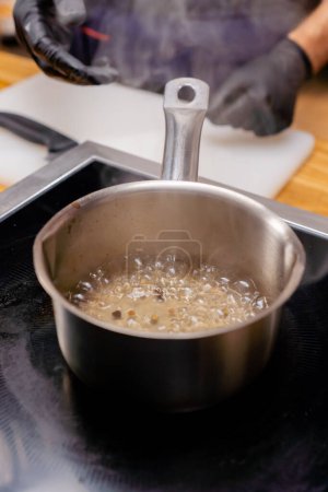Foto de Primer plano de una olla con una manija en la estufa con alcohol y especias hirviendo - Imagen libre de derechos