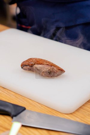 Photo for Beautiful piece of fried duck breast steaming on a white board professional cooking - Royalty Free Image
