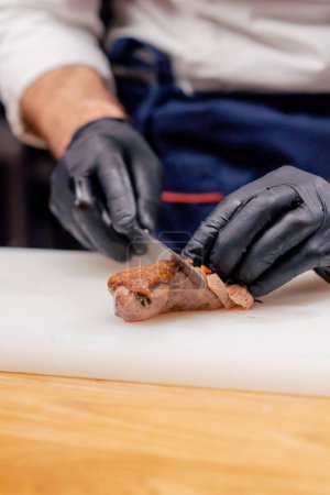 Foto de Cuchillo cortando un hermoso pedazo de pechuga de pato asado humeante en una pizarra blanca - Imagen libre de derechos