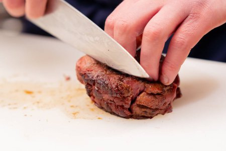 Foto de Primer plano de corte profesional carne de res cocida con cuchillo en la pizarra blanca - Imagen libre de derechos