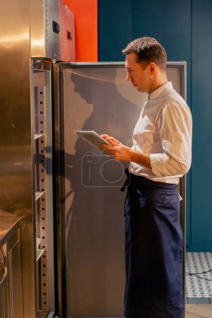 Foto de Chef de cocina profesional mira en la nevera y elige los ingredientes para cocinar concepto de alimentos - Imagen libre de derechos