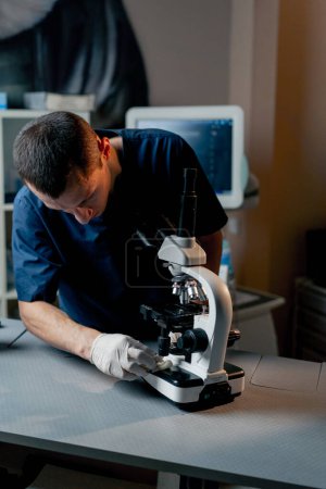Photo for In a veterinary clinic a young doctor adjusts the coarseness in a microscope - Royalty Free Image