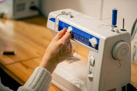 Photo for In a sewing workshop seamstress switches cutting modes on a machine - Royalty Free Image
