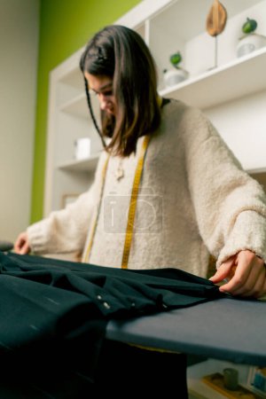 in a sewing workshop a seamstress folds black fabric for corrugation